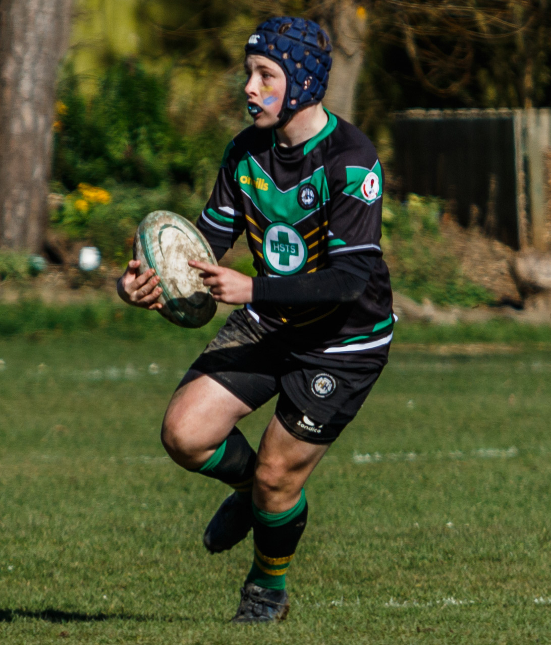 A boy on a rugby pitch holding a rugby ball